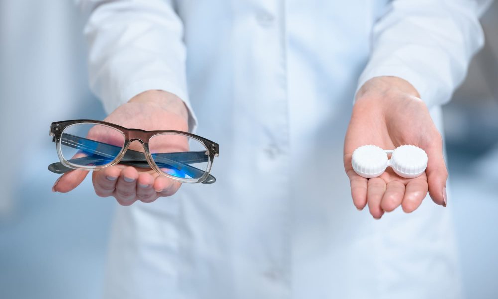 A woman in a lab coat holding a pair of contacts.