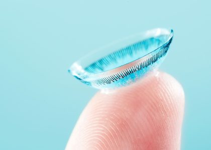 A person's finger with a small soft contact lens on it.