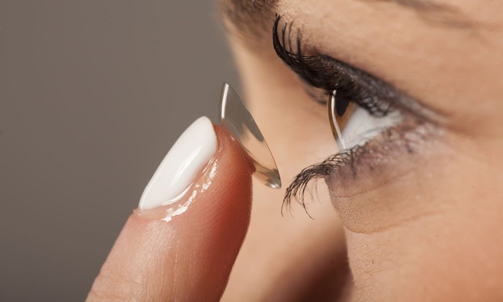 A woman is putting multifocal contact lenses on her eye.