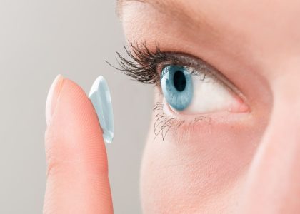A woman is choosing and holding a contact lens for her eye.