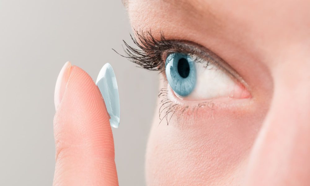 A woman is choosing and holding a contact lens for her eye.