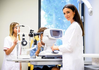The Eye Pros - Eye care professional in Twin Falls conducting an eye examination with a patient using specialized equipment while an assistant takes notes.