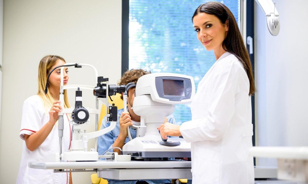 The Eye Pros - Eye care professional in Twin Falls conducting an eye examination with a patient using specialized equipment while an assistant takes notes.