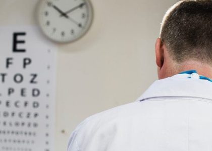 An eye doctor looking at an eye chart during an appointment.