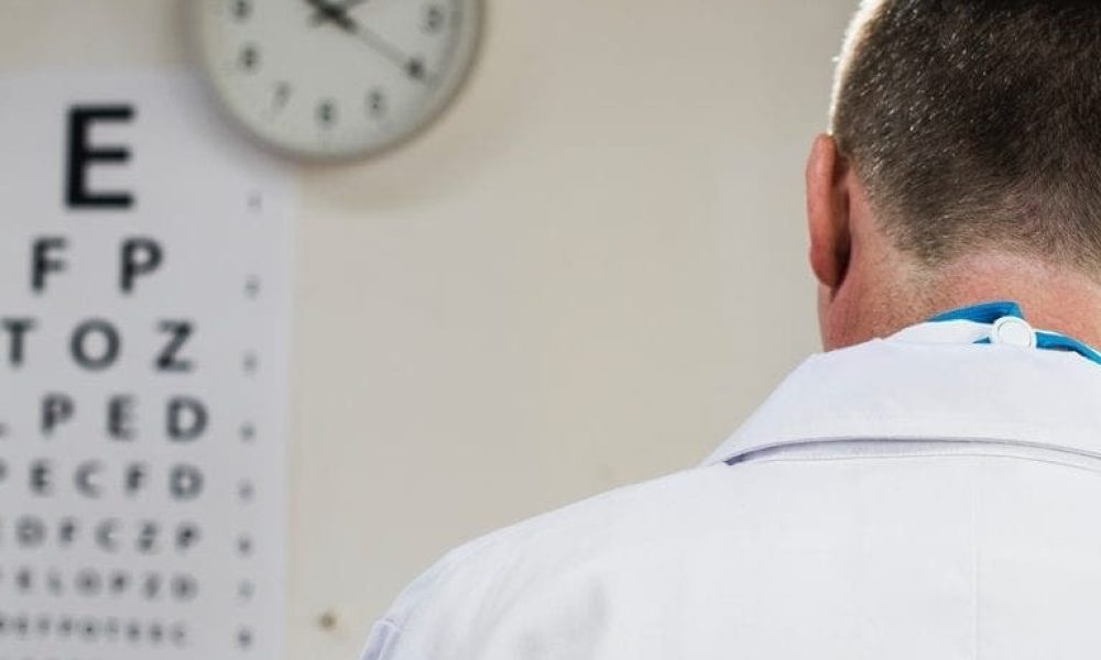 An eye doctor looking at an eye chart during an appointment.